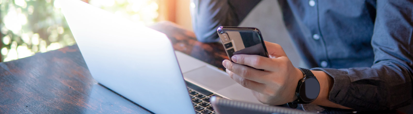 man holding phone at laptop